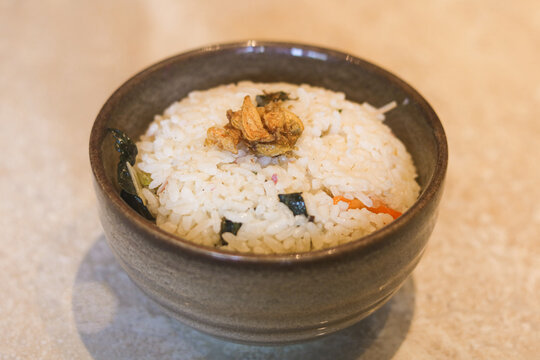 A bowl of Nasi Liwet, a traditional Indonesian fragrant rice dish served in a rustic ceramic bowl.