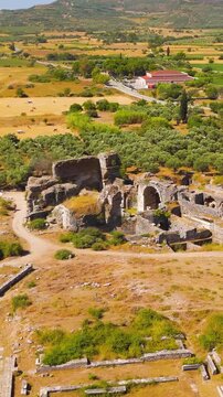 Vertical video. Balat, Turkey. Wide aerial drone shot over the Baths of Faustina complex, center of social life and sports in Roman Miletus. Aerial View, Point of interest. Rich colors