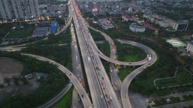 Aerial perspective of Phap Van Cau Gie interchange merging with Hanoi Ring Road 3 during evening traffic with dense urban surroundings and flowing vehicle lights