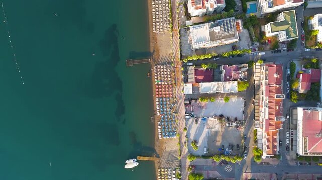 Marmaris, Turkey. Coastal urban landscape with pier, calm water, streets and hotels from above. Beaches with sunbed rows and morning atmosphere.. Aerial View, HEAD OVER SHOT with rotation