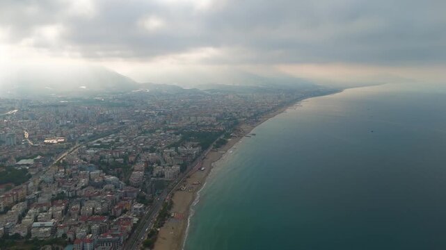 Alanya, Turkey. Aerial view showing low clouds over sea with sun rays illuminating Oba Beach, Tosmur Beach and cloud-covered mountains.. Aerial View