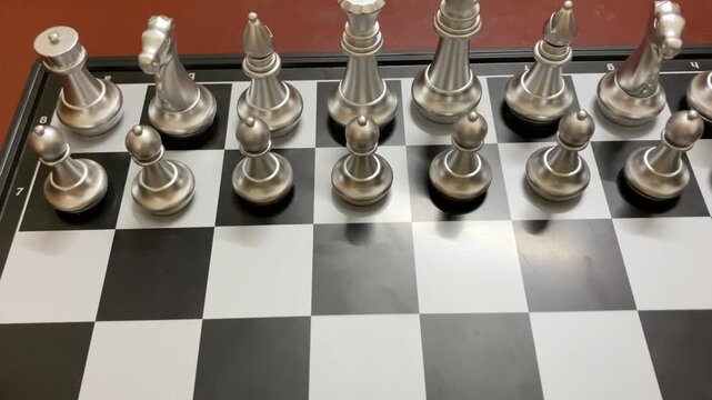Metallic silver and golden chess pieces arranged on checkered board - Close up shot.