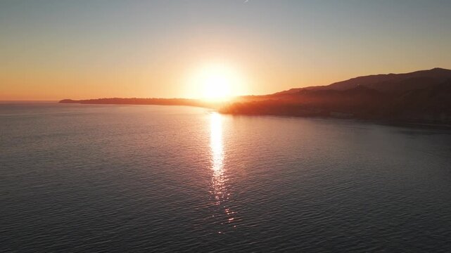 Low aerial dolly shot of the setting sun over Paradise Cove at Point Dume in Malibu, California. 4K