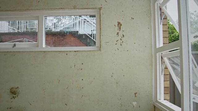 Worn interior wall in Sydney home showing stains, peeling paint and age-related decay. Natural light through windows highlights neglect, renovation potential and housing deterioration.