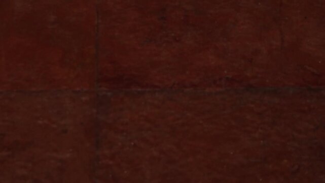 Macro shot of dark terracotta tiles. The image highlights a porous, weathered clay surface with visible grout lines and organic brown earth tones in a low-light, flat perspective.