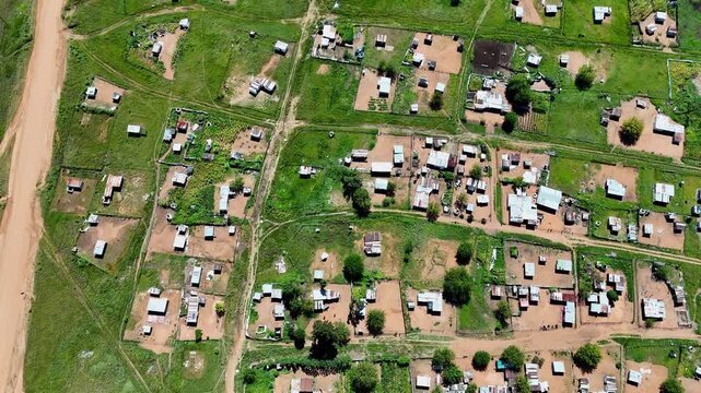 Top-down aerial view over informal settlement built next to dirt road in Africa