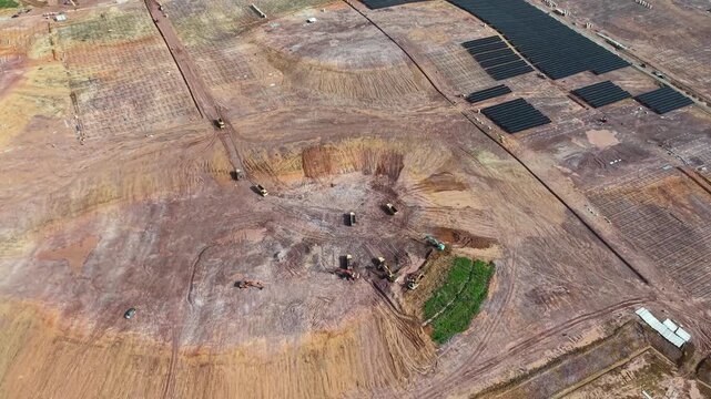 Drone aerial view of solar farm construction with excavators, trucks and partially installed panels