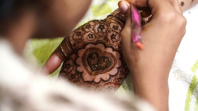A Hindu girl drawing mehendi design in hands in India