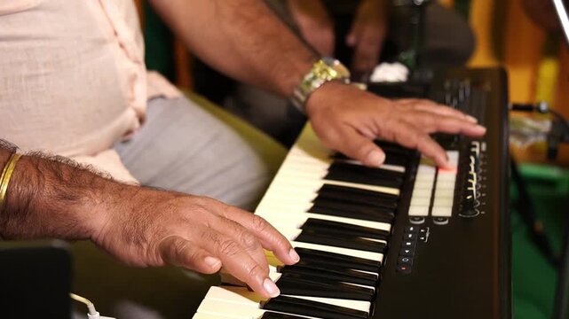 Close-up of a talented musician's hands playing a digital synthesiser during a musical performance in India.