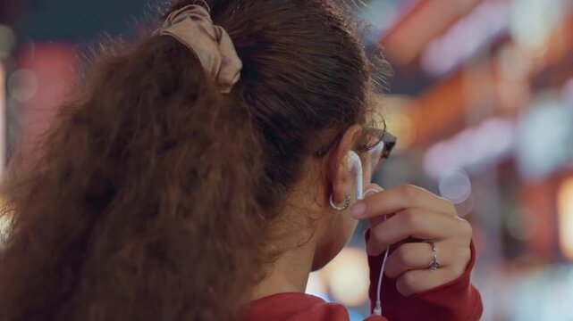 Black music fan with glasses listening to neon city, evening festival vibe and candid profile with earbuds, soft bokeh lights, crowded street background and relaxed urban exploration