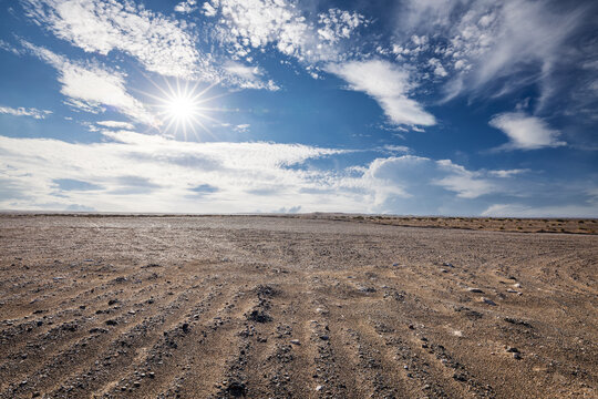 Bright sun shining over a vast desert landscape under a clear blue sky