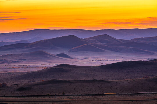 Beautiful grassland and mountain landscape under a dramatic sunrise sky, Inner Mongolia, China.