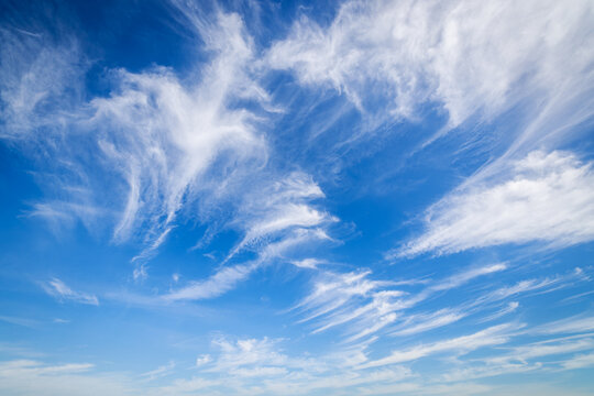 Blue sky background with white wispy cirrus clouds on a bright sunny day