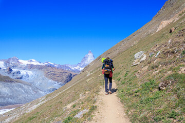 Fototapeta premium Mountain panorama with hiking mountaineer and Matterhorn in Pennine Alps, Switzerland