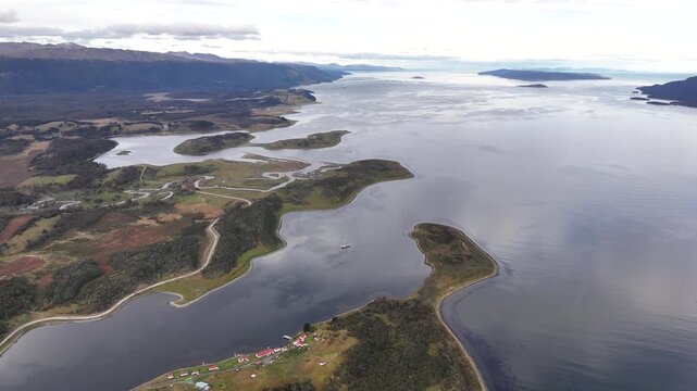 Cinematic aerial flying forward over the intricate inlets of Bahia Harberton toward the expansive waters of the Beagle Channel and the remote mountains of Tierra del Fuego