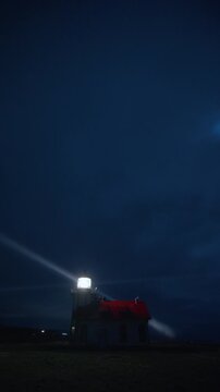 Vertical Screen: Lighthouse beacon shining through night fog in vertical frame near Mendocino, California, USA creating strong light rays and atmospheric coastal scene