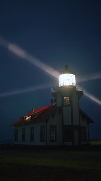 Vertical Screen: Night lighthouse glowing with bright rotating beam cutting through coastal fog near Mendocino, California, USA creating dramatic and atmospheric coastal scene