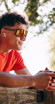 Happy man, fitness or listening with earphones or phone in nature for music or outdoor workout break. Active, male person or smile with mobile smartphone or earpods for audio streaming or sound app