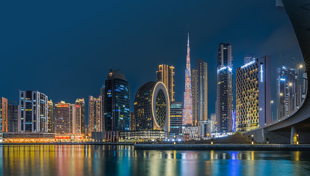 Modern buildings in the city center of Dubai in the evening. Illuminated skyscrapers in the financial center at the blue hour. View of skyline in united arab emirates at night and reflection
