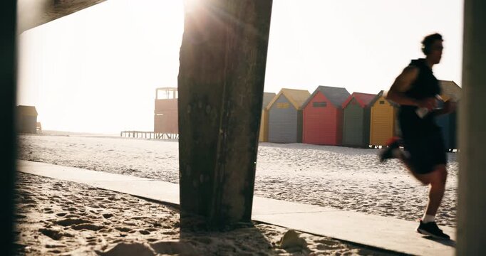Fitness, man and running with headphones at beach for speed challenge, interval training or cardio. Water, runner and sprint with music at seaside for athletic performance, pace workout and sun flare