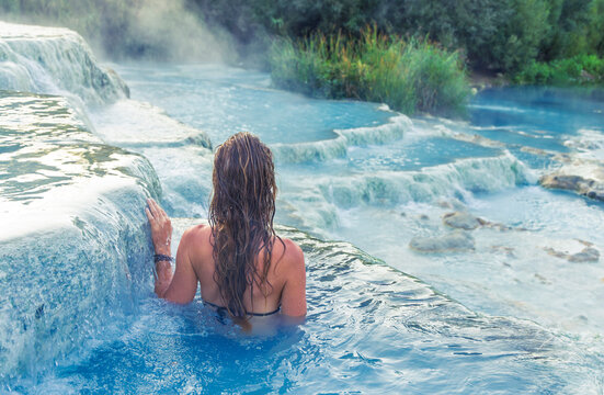 Young woman relaxing in the turquoise thermal waters of Saturnia, Tuscany, Italy; natural hot springs and wellness spa concept.