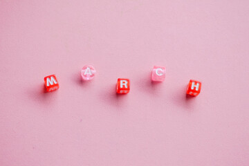 March Month Spelled with Red and Pink Alphabet Beads on Pink Background © Afi