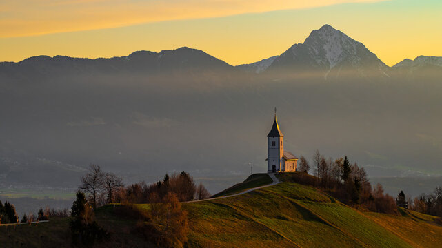Sunrise at Jamnik Church in Slovenia with pastel sky and alpine landscape