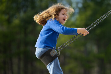 Happy child enjoying a fun ride. Happy kid on playground. Carefree kid swinging in the air. Happy...