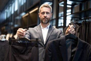 Mature man in a suit in a suit boutique. A businessman confidently chooses elegant suit in store. A...