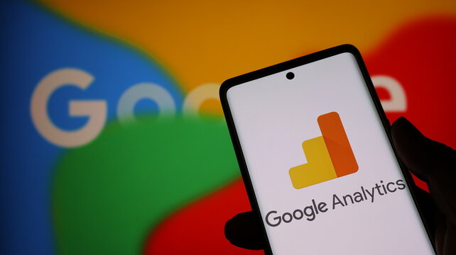 Hand holding smartphone with google analytics app on screen in front of google logo background