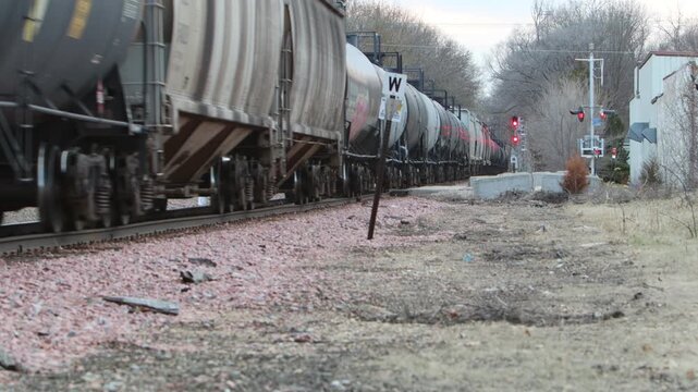 A super long train going down railroad tracks with never ending freight cars disappearing into the distance.