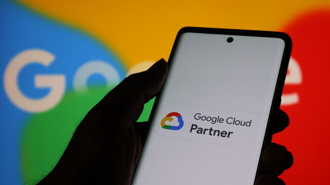 Hand holding smartphone with google cloud partner logo on screen in front of colorful google logo background