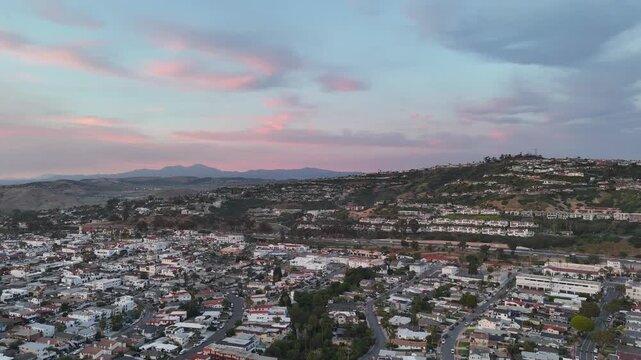 Aerial view of San Clemente at sunset, featuring hillside neighborhoods, dense town streets, and Saddleback Mountain in the distance beneath pink and blue evening clouds in Orange County.