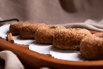 A delectable stack of freshly baked cinnamon sugar donuts presented on a rustic wooden tray.