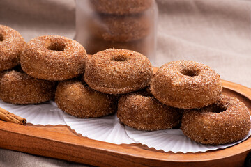 A delectable stack of freshly baked cinnamon sugar donuts presented on a rustic wooden tray.