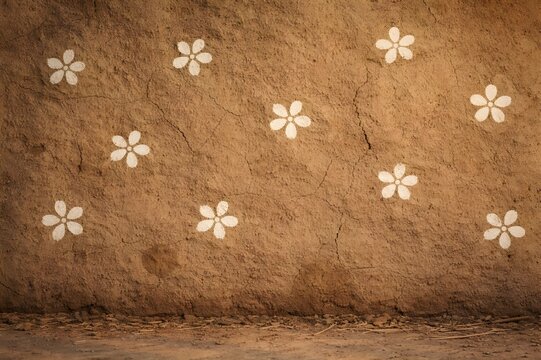 Hand-painted white floral motifs on sun-dried village mud wall surface