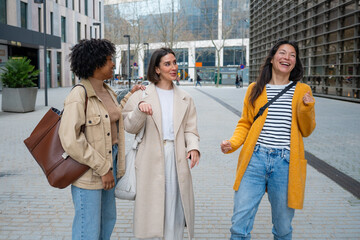 Diverse women friends laughing walking city street