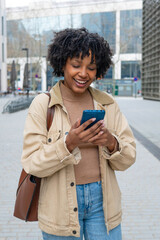 Young black woman smiling using smartphone outdoors