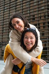 Happy young women enjoying piggyback ride in city