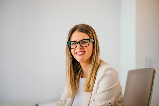 Professional woman wearing glasses smiling in office achieving success