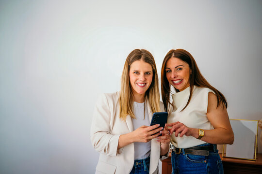 Women friends smiling using mobile phone technology