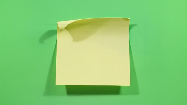 Minimalist Yellow Sticky Note on Green Background Close-up Shot Video
