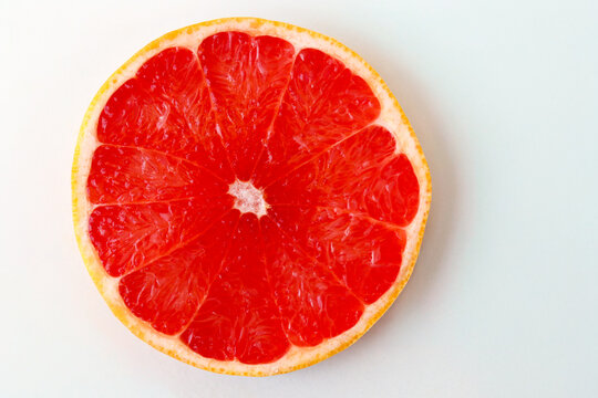 Freshly cut grapefruit slices isolated on a white background, bright pink or red citrus fruit pieces with juicy texture, healthy natural food concept.