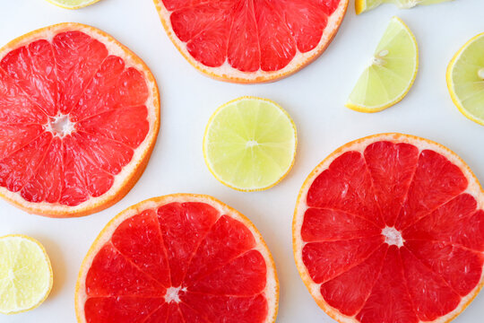 Freshly cut grapefruit slices isolated on a white background, bright pink or red citrus fruit pieces with juicy texture, healthy natural food concept.