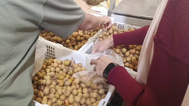 Close up hand at supermarket choose langsat fruit to buy