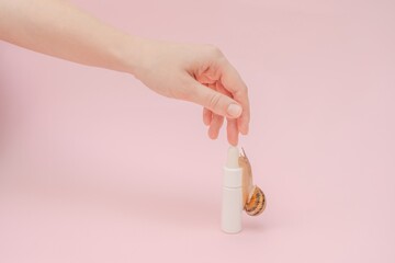 Cosmetic's bottle and snail on it with elegant hand. Mockup for brand. Skin care, spa, luxury cosmetic, natural beauty product © Antonio