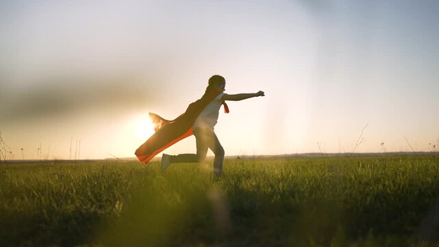Child running with cape across field at sunset silhouette framed by low grass and sunlight near horizon expressing imagination and play with motion and freedom icon of imagination and play joy