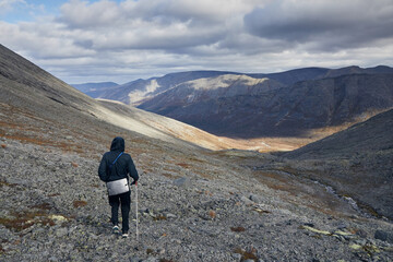 Fototapeta premium A tourist in a black jacket walks through the mountains
