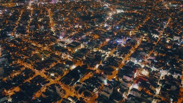 Top down aerial view of dense urban buildings at night in Nha Trang, Vietnam
Warm street lights illuminate the narrow alleys and rooftops of the city center