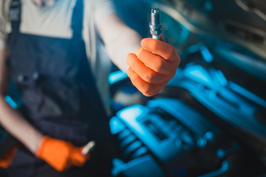Auto mechanic installing a new spark plugs into the engine.